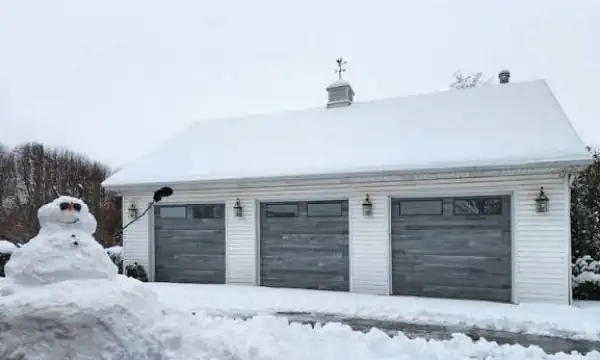 Three-car garage with snow-covered driveway and roof in winter