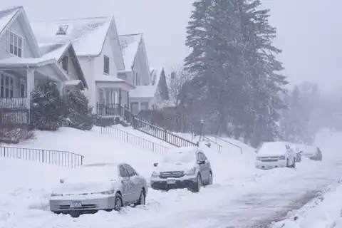 Snow-covered residential street and driveways during a winter storm
